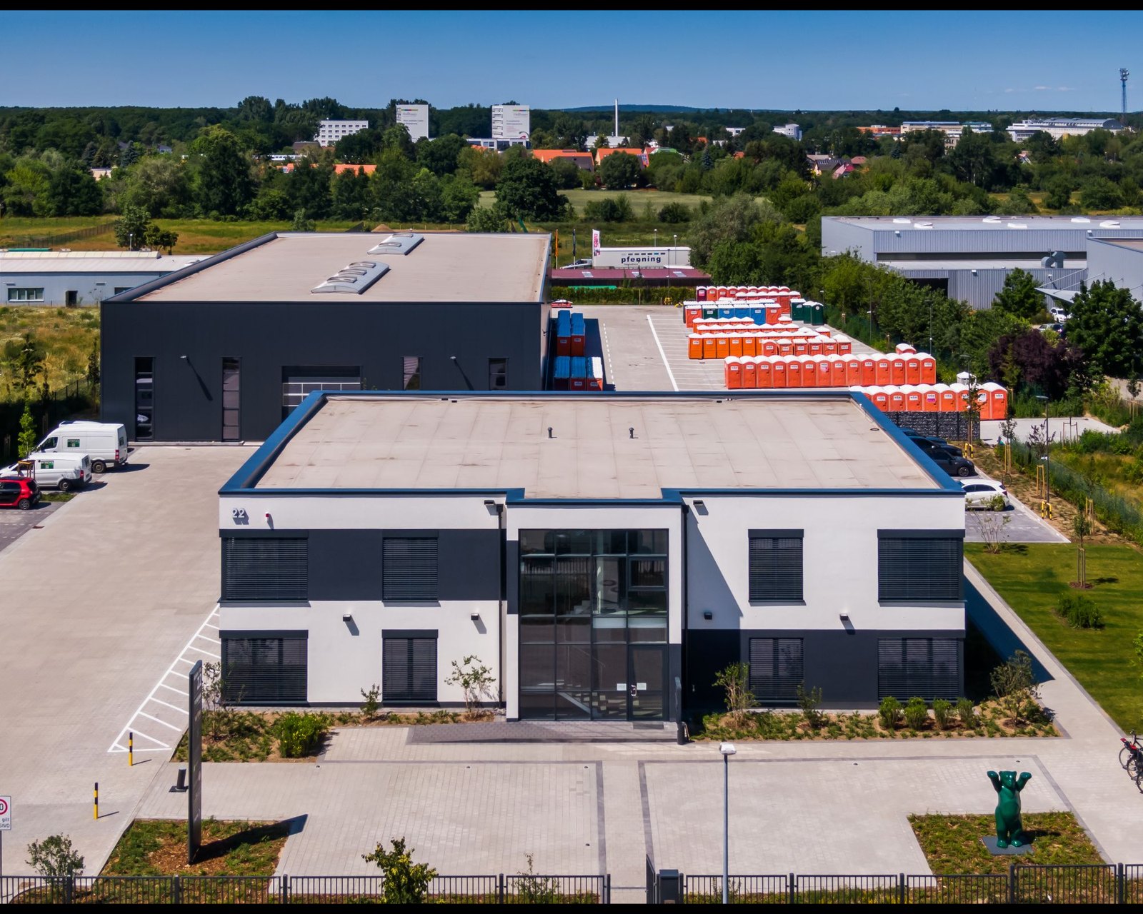 Luftaufnahme des Firmensitzes von W&W in der Kieler Straße 22 in Stahnsdorf: Bürogebäude, Halle und Betriebshof mit aufgereihten Toilettenkabinen