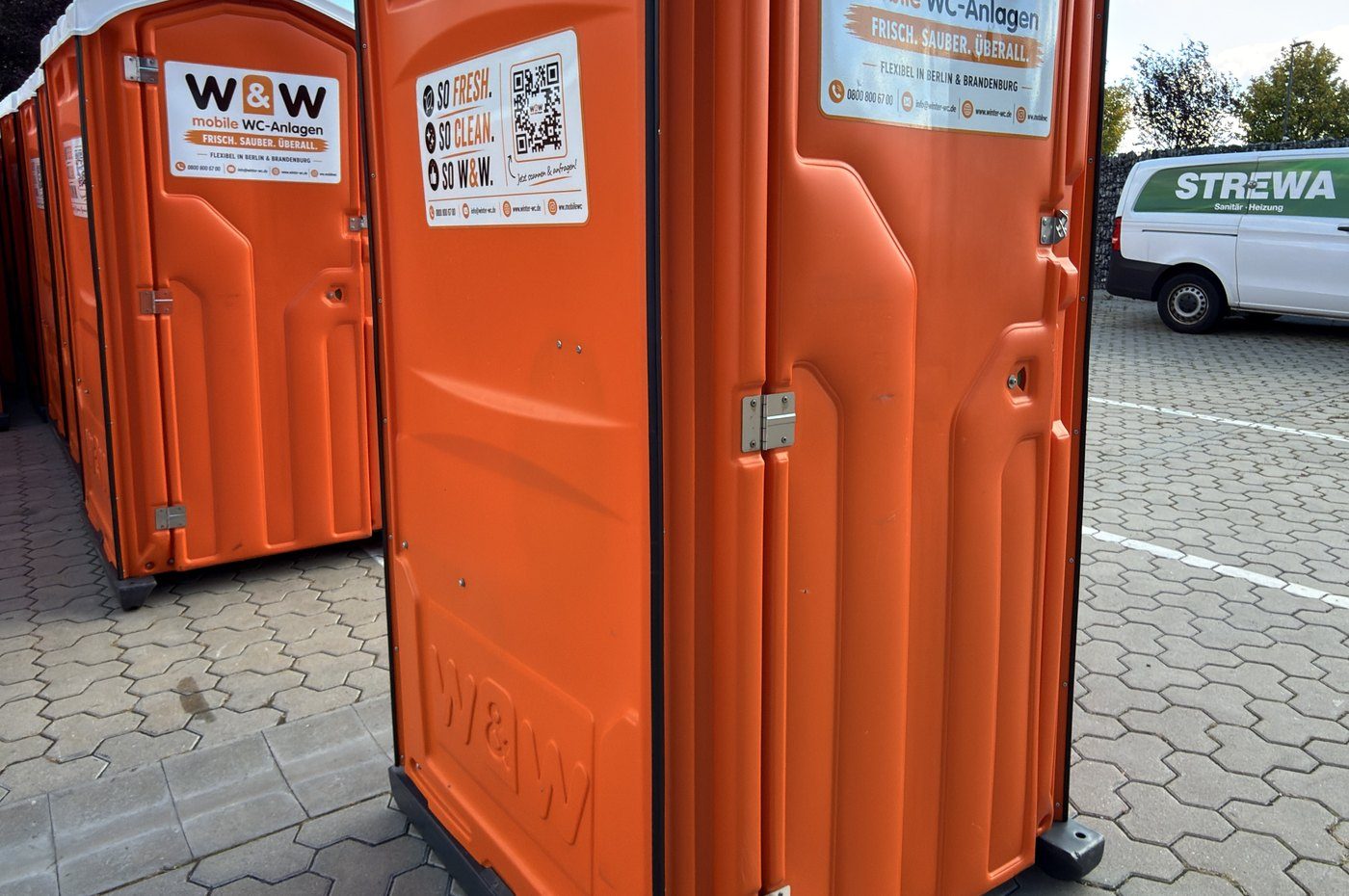 Orange W&W toilet cabins in the depot yard, a van in the background
