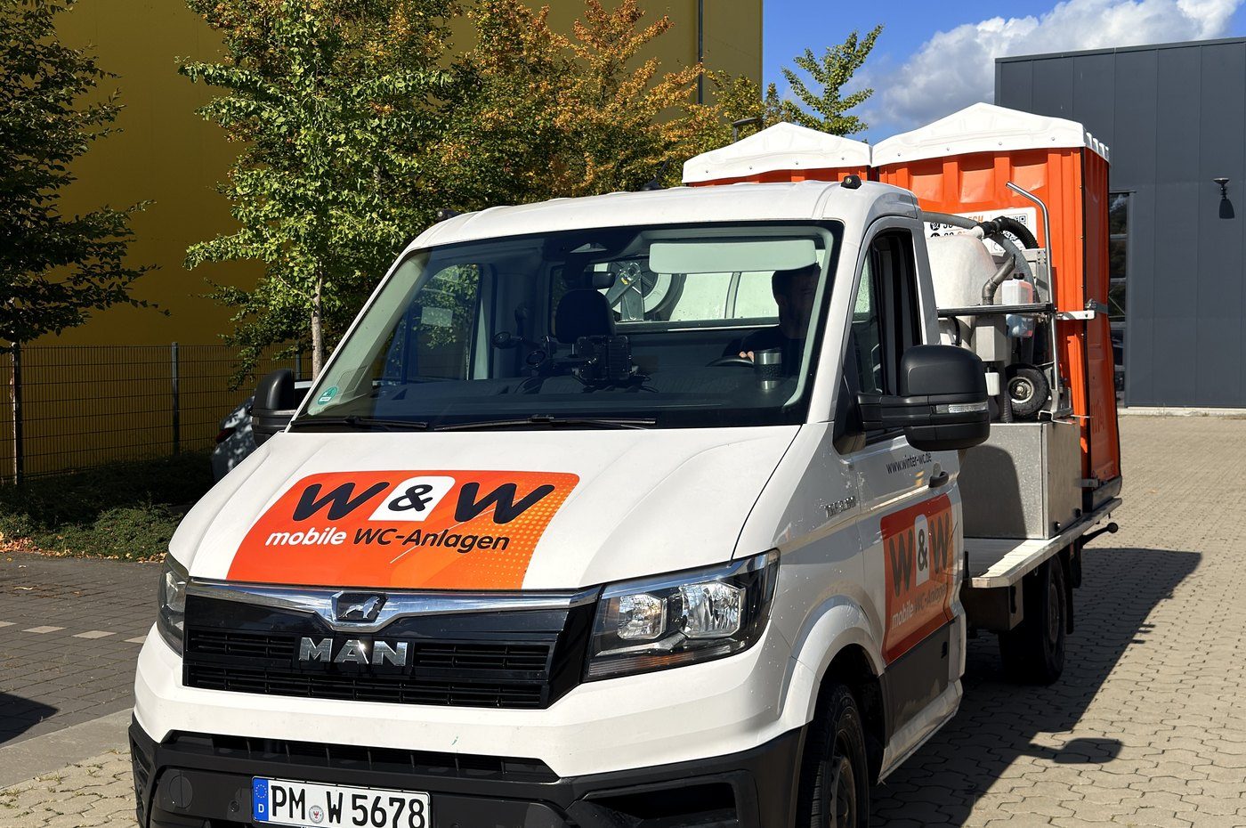 W&W service vehicle with toilet cabins on the loading bed in front of the depot