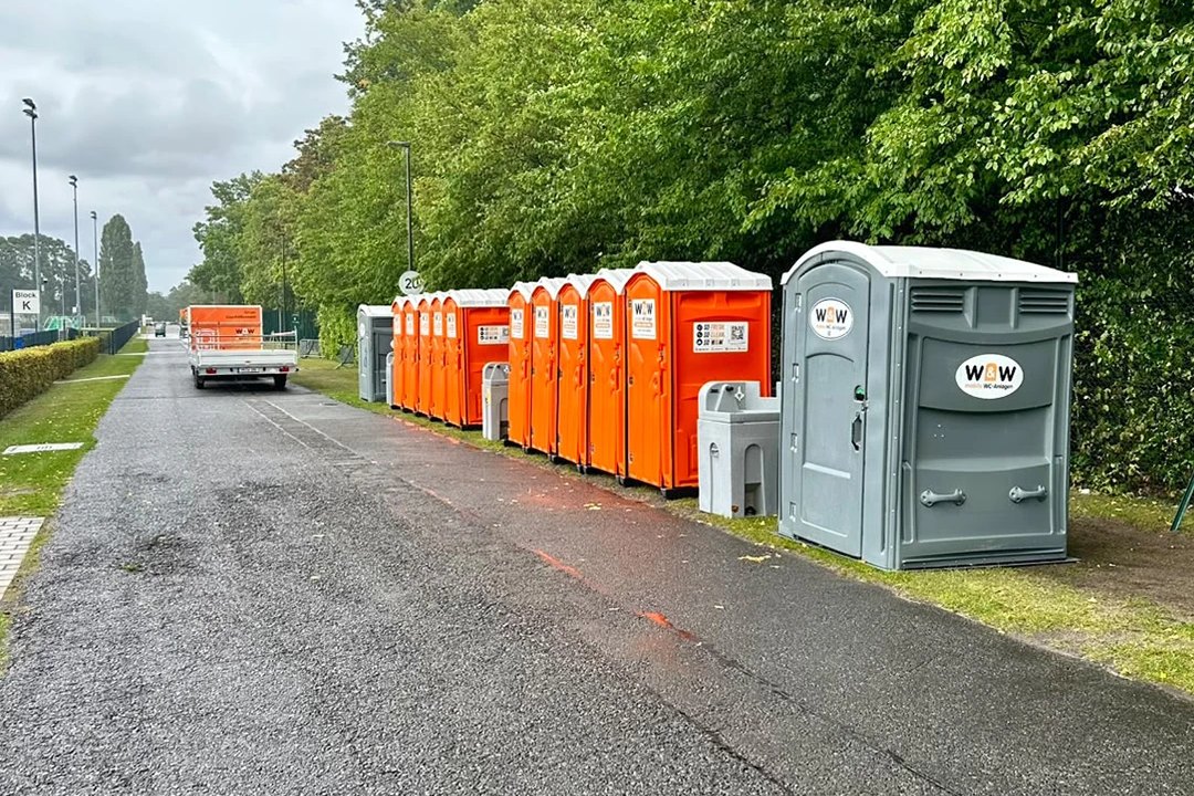 Row of W&W toilet cabins with an accessible cabin and a hand-wash station at the event grounds